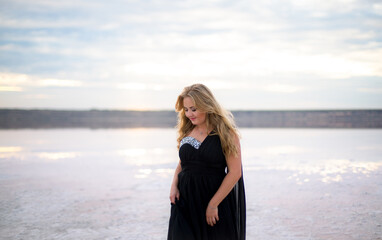 plump caucasian female in a black dress on a salty still water lake at sunset