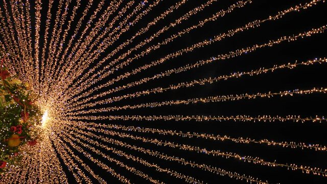 Beautiful illumination in the form of a tent over the New Year tree in the city.