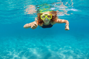 Young girl in snorkeling mask dive in coral reef sea lagoon to explore underwater world. Family...