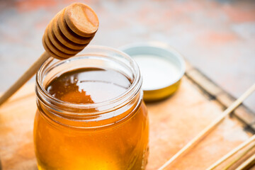 Jar with freshly harvested liquid honey on the old wooden table. Selective focus.
