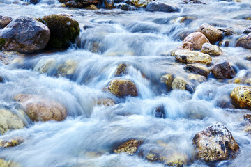 background - a mountain stream in a rocky channel, the water is blurred in motion