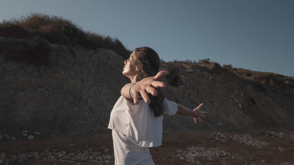 Young woman with outstretched hands doing yoga in early morning on the beach. High quality photo