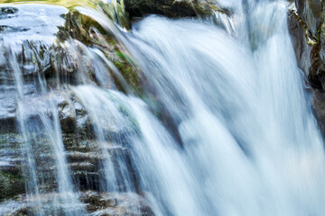 waterfall blurred in motion flows down the rocky ledges, close-up