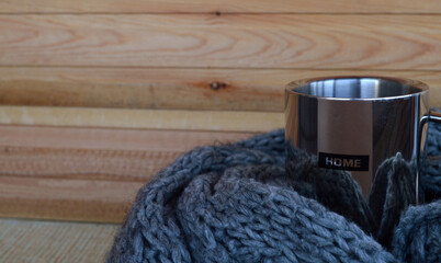 Iron mug with the inscription House in a gray scarf on a background of aged wood