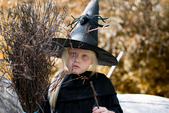 Halloween and witches. Girl in a black hat with a broom in his hands in the autumn forest