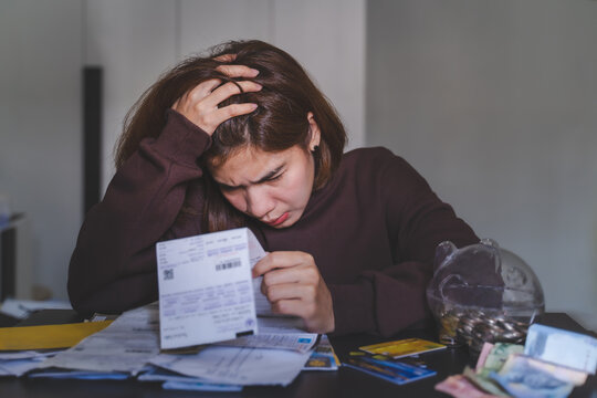 Young Woman Look At Many Bill For Online Shopping Payment Via Credit Card. She's Serious And Stress For This Expenses