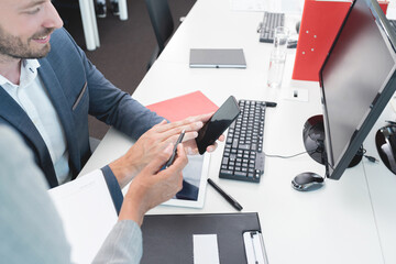 Businessman and businesswoman checking mobile phone