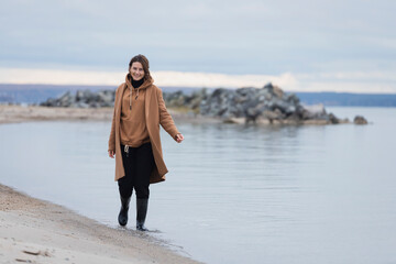 Atmospheric portrait of a young woman in  stylish clothers on a sandy beach near a blue sky on a...