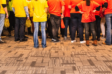 Group of back people with yellow and red colored pom poms.
