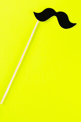 Black paper mustache on yellow background.Top view.Men's health awareness month. International men's day.