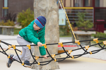 A nimble boy climbs a rope ladder in a hanging city on a playground.
