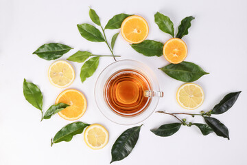 different types of fresh raw green tea leaf flower bud lemon orange slice transparent glass teacup saucer liquid tea on white background top view