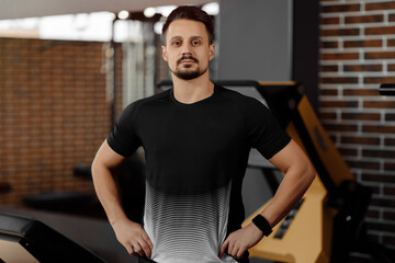 Portrait of personal trainer in sports outfit in fitness center gym standing strong