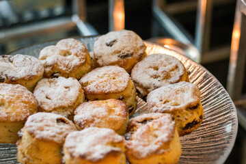 a plate of raisin scones dusted with icing sugar on display