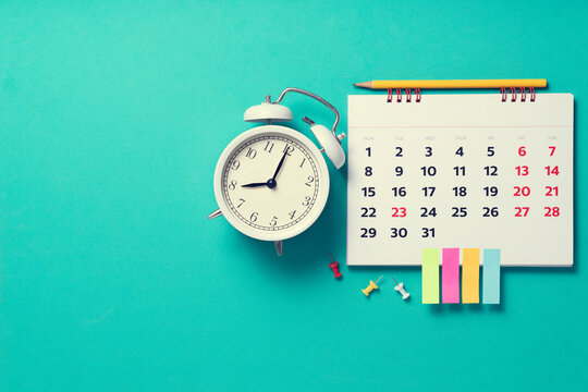 close up of calendar and alarm clock on the green table background, planning for business meeting or travel planning concept