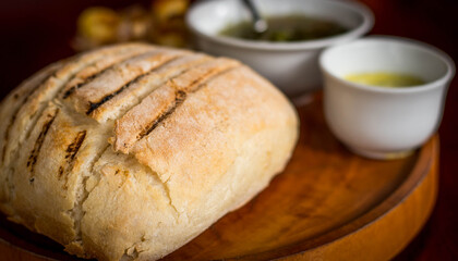 a loaf of bread with olive and butter on the side on a wooden block