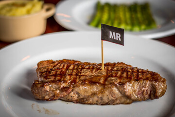 a slab of ribeye beef steak done to medium rare served on a plate