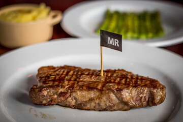 a slab of ribeye beef steak done to medium rare served on a plate