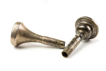 Two vintage trombone mouthpieces laying down on a white surface.  Close up of brass instrument mouthpiece with patina and wear.  Musical instrument accessories up close. - obrazy, fototapety, plakaty