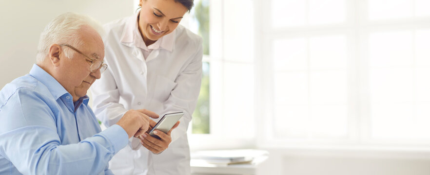 Friendly Doctor Teaching Senior Man To Use Special Mobile App For Tracking Various Health Indicators