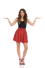 Naklejka premium Beautiful Young Woman In Mini Skirt And High Heels Is Standing With Hands Raised