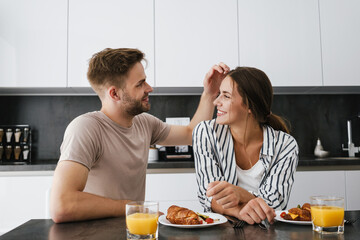 Young caucasian couple sitting at table while having breakfast at home