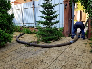  Image of the courtyard of a private house where a sewer well is pumped out. Septic tank outside the gate.  person on the street