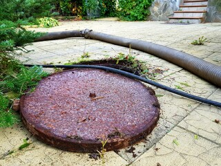 Open sewer manhole. An iron manhole cover is located nearby. Cleaning of garbage pits.