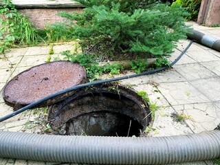 Image of the courtyard of a private house where a sewer well is pumped out. Septic tank outside the gate