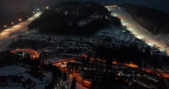 Night illumination cityscape center square mountain popular ski resort. Details of modern house among dark canyon tourist village.