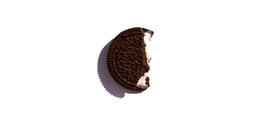 Bite a cookie consisting of two parts and a creamy layer in the middle. Chocolate crumbly cookies on a white background. Half a round dark chocolate cookie isolate.