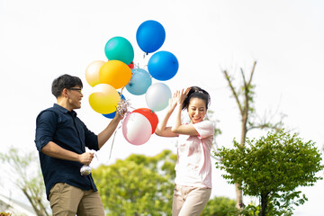 Asian Couple playing and tease each other with balloon in the garden