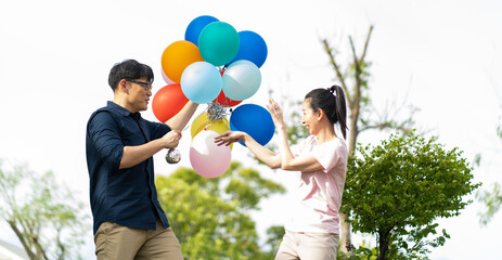 Asian Couple playing and tease each other with balloon in the garden