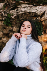 model sitting on the field ground with a stone in the background
