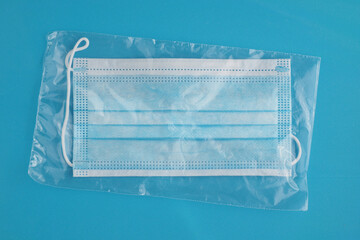 New protective face mask In transparent pouch. Blue background.