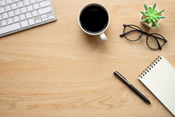 Top view above of Wooden office desk table with keyboard, notebook and coffee cup with equipment other office supplies. Business and finance concept. Workplace, Flat lay with blank copy space...