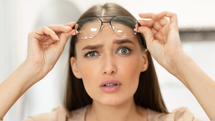 Portrait of confused young woman looking through spectacles