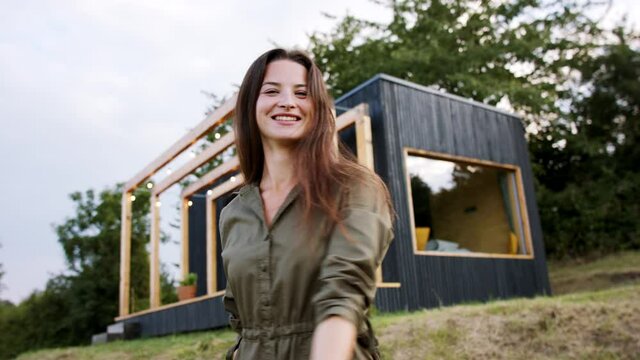 Young woman spinning outdoors, weekend away in container house in countryside.