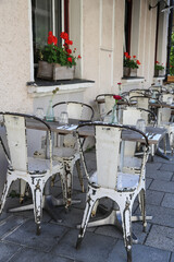 Charmantes vintage outdoor Restaurant mit verwitterten weißen Stühlen und Holztischen dekoriert mit Gläsern, Blumenvasen, Bestecken und Servietten