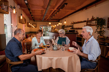 Four caucasian senior people eating healthy food at a restaurant. Food and drink concept.