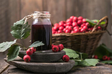 Hawthorn berries  tincture or infusion bottle and basket of thorn apples on wooden board. Herbal medicine.