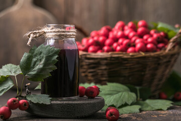 Hawthorn berries  tincture or infusion bottle and basket of thorn apples on wooden board. Herbal medicine.