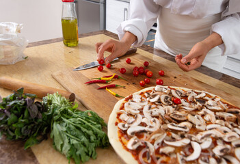 Close-up on the hands of the chef choosing tomatoes for pizza. Vegan food.