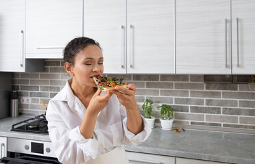 A young woman chef tastes a vegan pizza without cheese and closed her eyes in delight ..