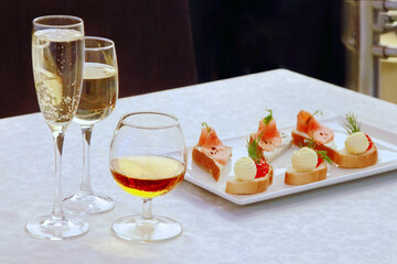 Alcoholic drinks in glasses and snack with red caviar, fish and butter on bread.