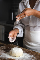 View of the cook's desk. The photo shows the hands of the cook sprinkling flour on the dough.