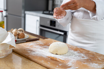 View of the kitchen table with a ball of dough on a wooden board.