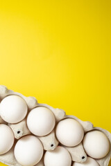 chicken eggs in a cardboard box with place for text on a bright yellow background. top view, close-up