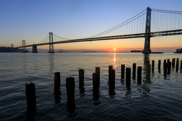 Sun rising behind Bay Bridge via The Embarcadero of San Francisco.