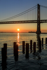 Fototapeta na wymiar Sun rising behind Bay Bridge via The Embarcadero of San Francisco.